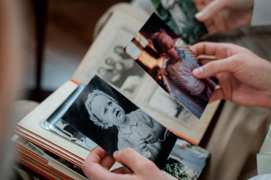 Parent standing in a quiet home after children leave, reflecting near family photos